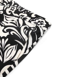 Detailed close-up showing high-waist stitching and baroque floral print on black fabric