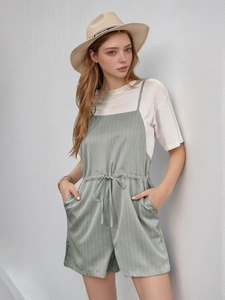 Detail eines hellgrün gestreiften Overalls mit Kordelzug und dünnen Schultergurten