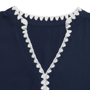 Détail du col en V avec broderie au crochet blanche sur une robe sans manches bleu marine