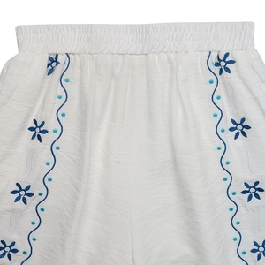 Détail de la taille élastique d'un pantalon blanc avec broderie florale bleue raffinée