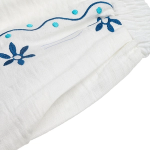 Vue détaillée du tissu texturé blanc avec broderie florale bleue et ourlet élastique plissé