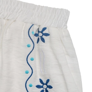 Détail de la taille élastique avec broderie florale bleue sur coton blanc pur