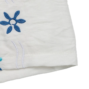 Gros plan détaillé de la broderie florale bleue sur un tissu blanc en coton et lin