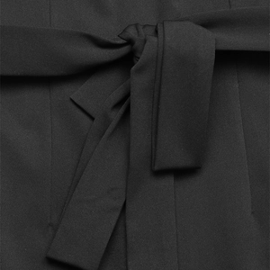 Detailansicht des schwarzen Jumpsuits mit Fokus auf den Bindegürtel und die Stofftextur