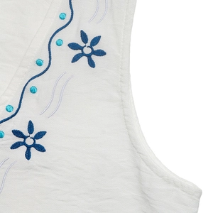 Gros plan détaillé d'une broderie florale bleue sur un tissu en coton et lin blanc