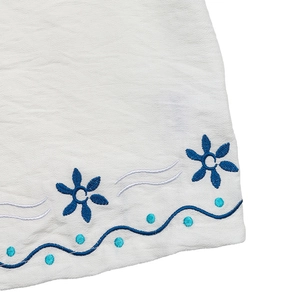 Gros plan détaillé de la broderie florale bleue et des coutures sur tissu blanc