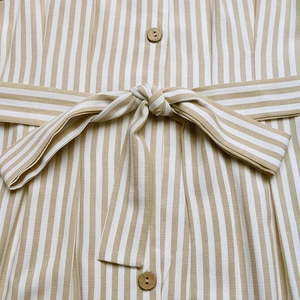 Detailed macro view of striped linen fabric with waist tie and wooden button accents