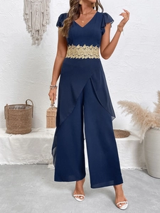 Dettaglio della tuta blu navy con pizzo dorato in vita e maniche a volant