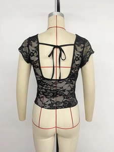 Détail de la dentelle florale et du nœud papillon au dos du crop top noir moulant