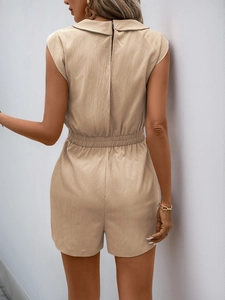 Detail of the back view of a beige romper showing the zipper and elastic waist texture