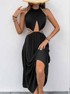 Détail d'une robe longue noire à licou avec découpes perlées ethniques et fente latérale