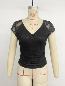 Détail du haut noir en dentelle à manches courtes avec col en V et motif floral ajouré