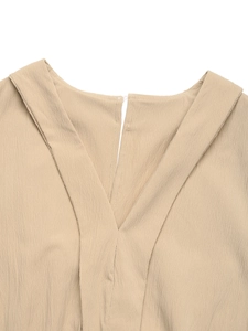 Detail of V-neckline on beige jumpsuit featuring premium crepe texture and clean seams