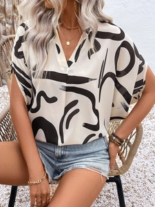 Macro shot of V-neck summer blouse featuring abstract black geometric print on beige fabric