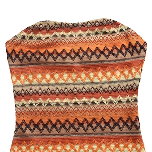 Détail d'une robe bustier en maille avec des motifs de vagues en orange et marron