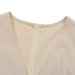Detail view of V-neckline on beige crinkle fabric romper with hidden zipper closure