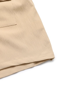 Close-up of beige summer jumpsuit fabric showing pleated texture and stitching details
