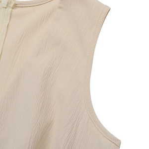 Detail view of beige v-neck romper with vertical crepe texture and hidden zipper closure