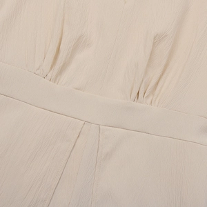 Macro view of light beige crepe fabric showing detailed pleating and neat stitching