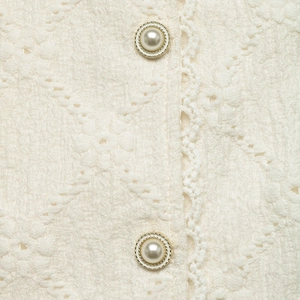 Detail of off-white lace texture with elegant gold-rimmed pearl buttons on a shirt