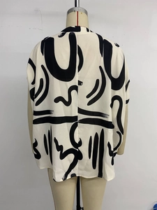 Detail of loose-fit beige blouse with black abstract wave patterns on lightweight chiffon