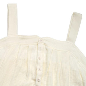 Gros plan du tissu texturé avec boutons sur une combinaison dos nu sans manches crème
