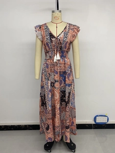 Détail du col en V avec glands blancs et imprimé paisley bohème sur la robe longue