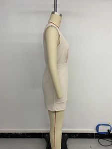 Detailed side view of beige sleeveless short jumpsuit featuring waist pleats on mannequin