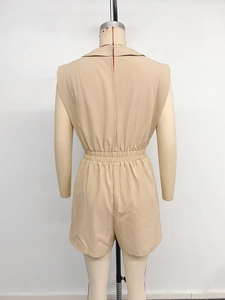 Detail view of the back of a beige sleeveless romper with zip and elastic waist