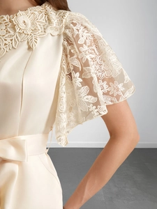 Gros plan du corsage en satin crème avec manches en dentelle et broderies florales