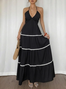 Détail d'une robe maxi plissée noire avec bordure ondulée blanche et col licou texturé