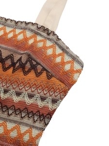 Detail of colorful ethnic zigzag embroidery and beige strap on summer jumpsuit fabric