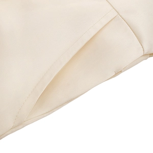 Gros plan sur la poche latérale d'une combinaison en satin crème avec coutures précises
