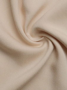 Close-up detail of soft beige fabric showing fine twill texture and silky smooth drape