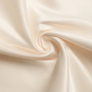 Gros plan sur le tissu en satin crème élégant avec texture soyeuse et détails plissés
