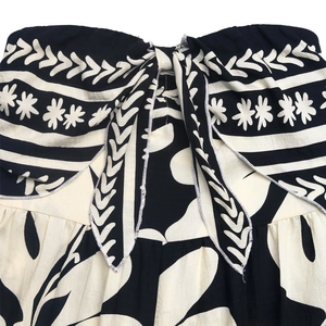 Detail of floral print jumpsuit featuring a bow-knot tie and smocked tube top fabric texture