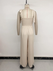 Detail of adjustable bow straps and elastic smocked back on apricot wide-leg jumpsuit