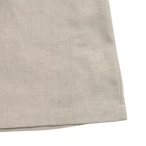 Close-up of beige linen fabric texture and high-quality hem stitching on the jumpsuit