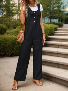 Detail view of black linen overalls featuring wooden buttons and practical side pockets