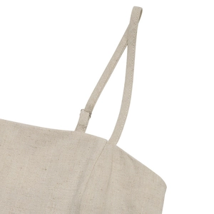Detail of beige linen romper featuring adjustable thin straps and textured fabric surface