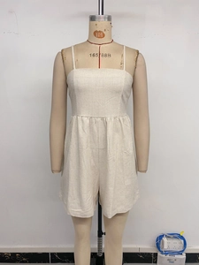 Detail of beige cotton-linen romper featuring thin straps and pleated high-waist design