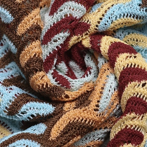 Detailed macro view of bohemian dress featuring colorful wavy knit patterns and hollow texture