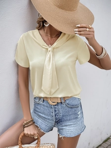 Detail of elegant pale yellow satin short sleeve shirt with scarf neck tie and silky texture