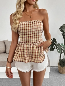 Detail of a plaid peplum tube top styled with white fringed denim shorts in a cozy setting