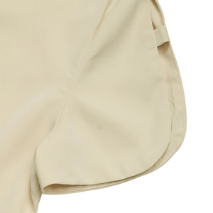 Detail shot of apricot summer shirt showing curved hem, fine stitching, and side strap design