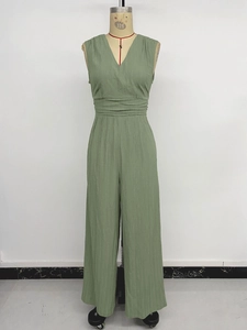 Close-up of smocked high waist and vertical texture on avocado green V-neck jumpsuit
