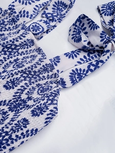Détail de robe fleurie bleue avec bustier smocké élastique et bretelles nouées aux épaules
