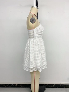 Detail view of white textured grid fabric and pleated waist on a mini dress