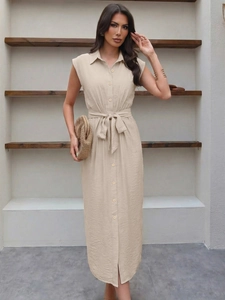 Détail de robe chemise beige mi-longue avec ceinture nouée et fente latérale