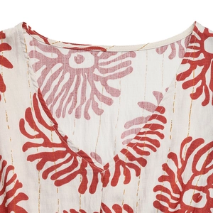 Détail du col en V avec imprimé corail rouge et rayures dorées sur tissu en coton-lin